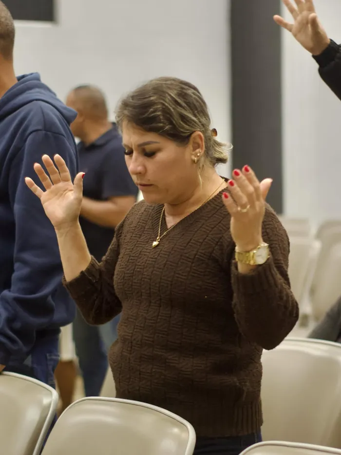 Mulher em oração de olhos fechados e mãos erguidas