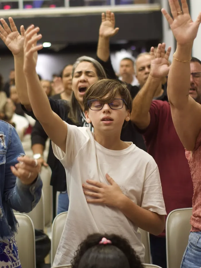 Templo cheio durante um culto, com a congregação de mãos erguidas
